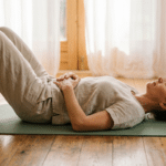 Woman practicing somatic yoga lying on mat with eyes closed — what is somatic yoga
